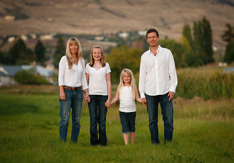 family of 4 wearing white shirts standing in a farmers' field