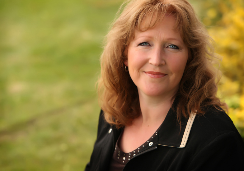 Business Portrait of a red haired woman wearing black in a green park setting