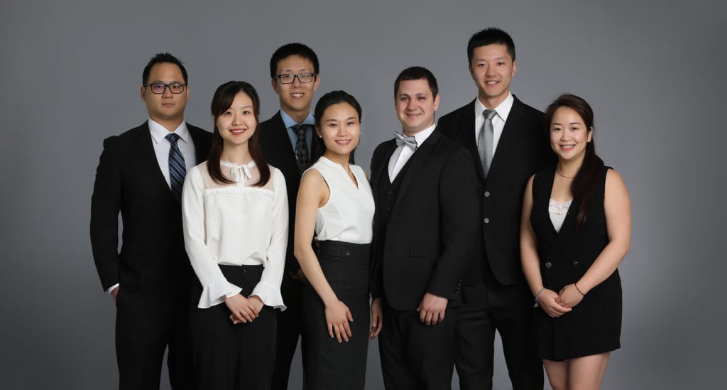 Business Portrait of a group of people wearing black suits and white shirts against a grey backdrop