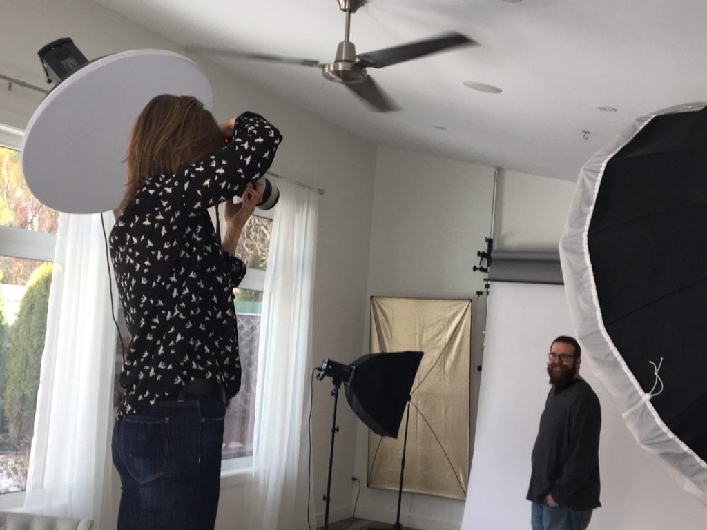 female photographer taking business headshot portrait photos in photography studio with windows